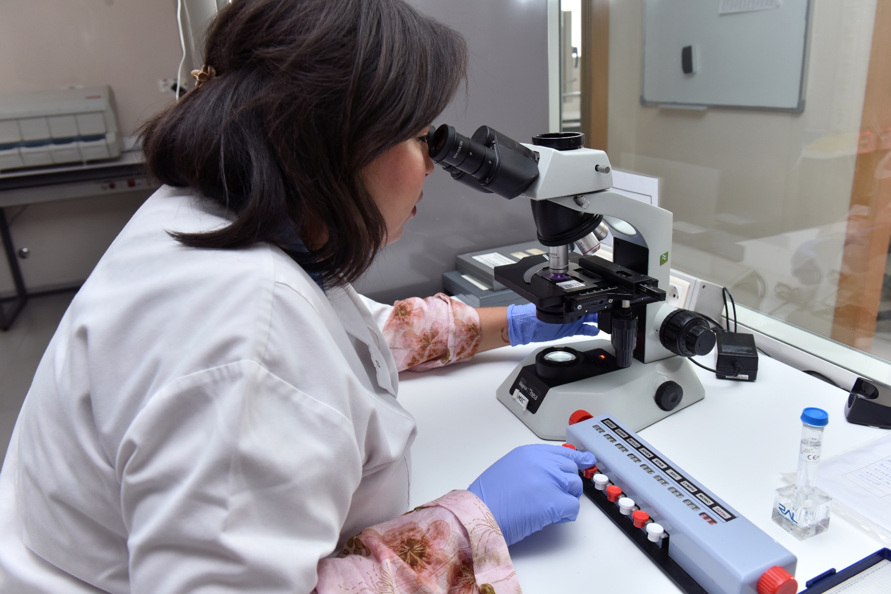 Biologiste médicale G Lab au microscope, contrôle qualité d'une analyse